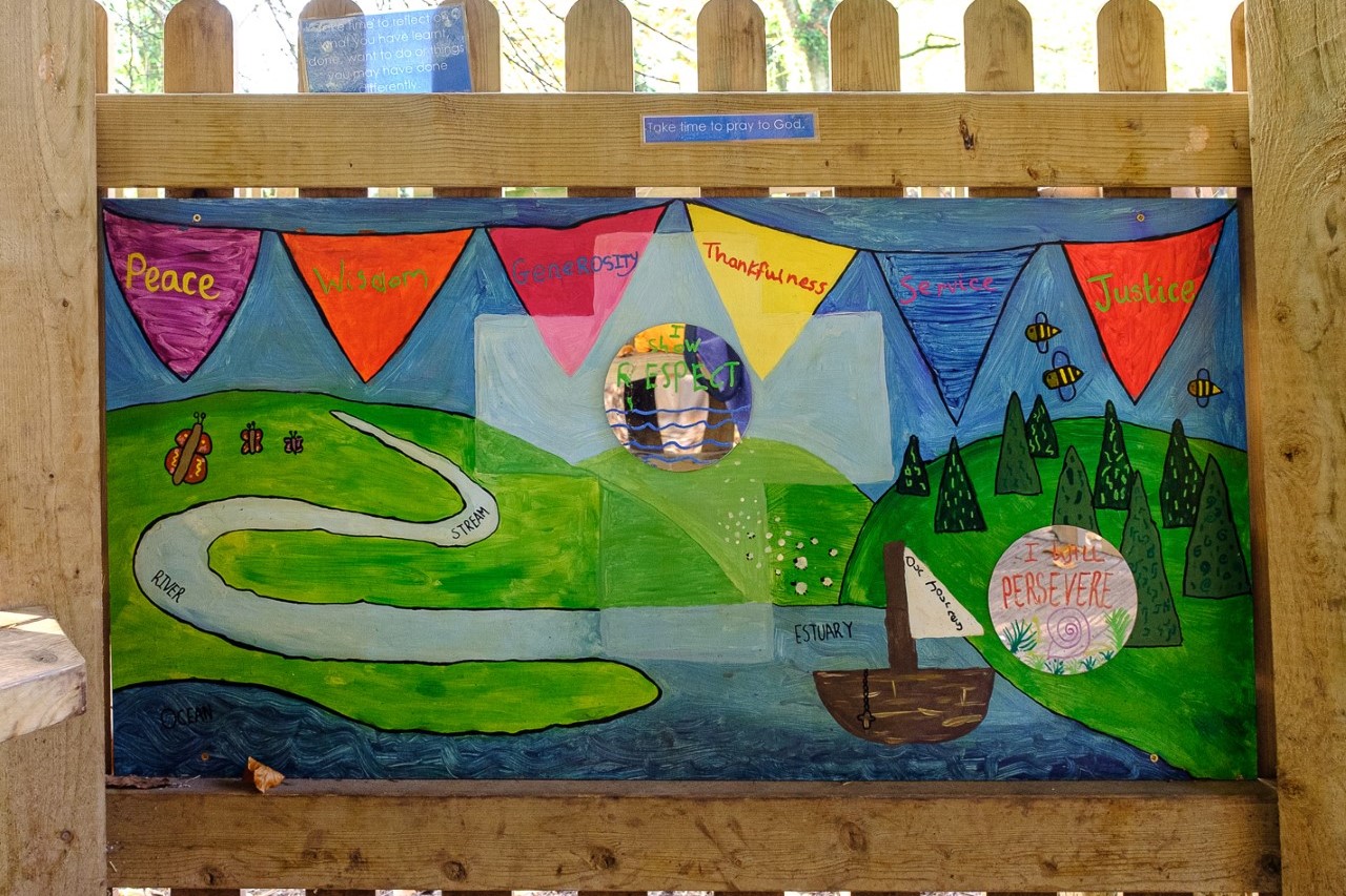 Colourful painting of rolling hills and a river by our pupils in our spiritual area