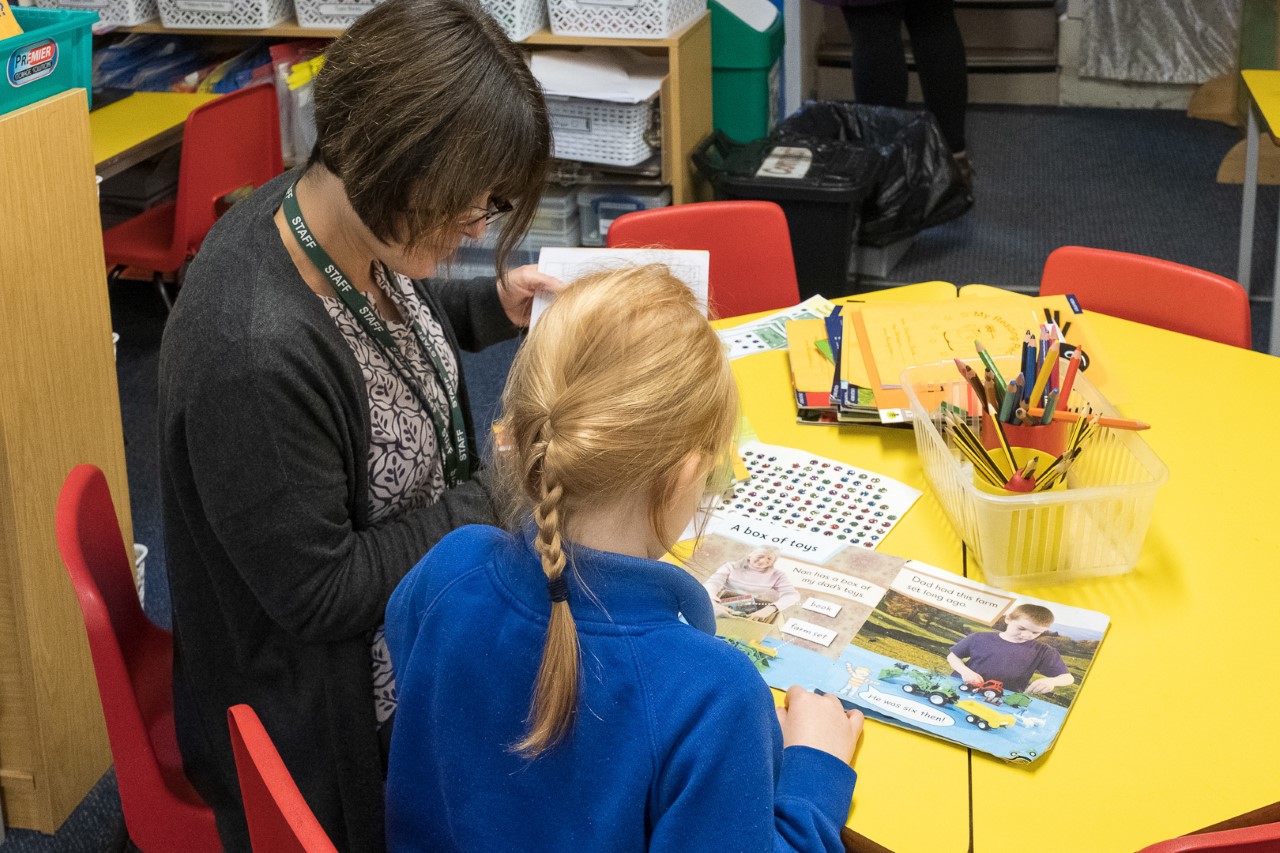 An early year pupil reading with her teacher