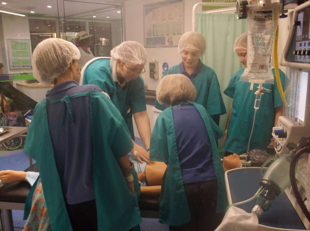 Pupils on a medical school trip in a mock hospital with a patient