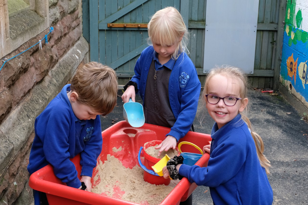 Early years pupils playing in the outdoor sandpit